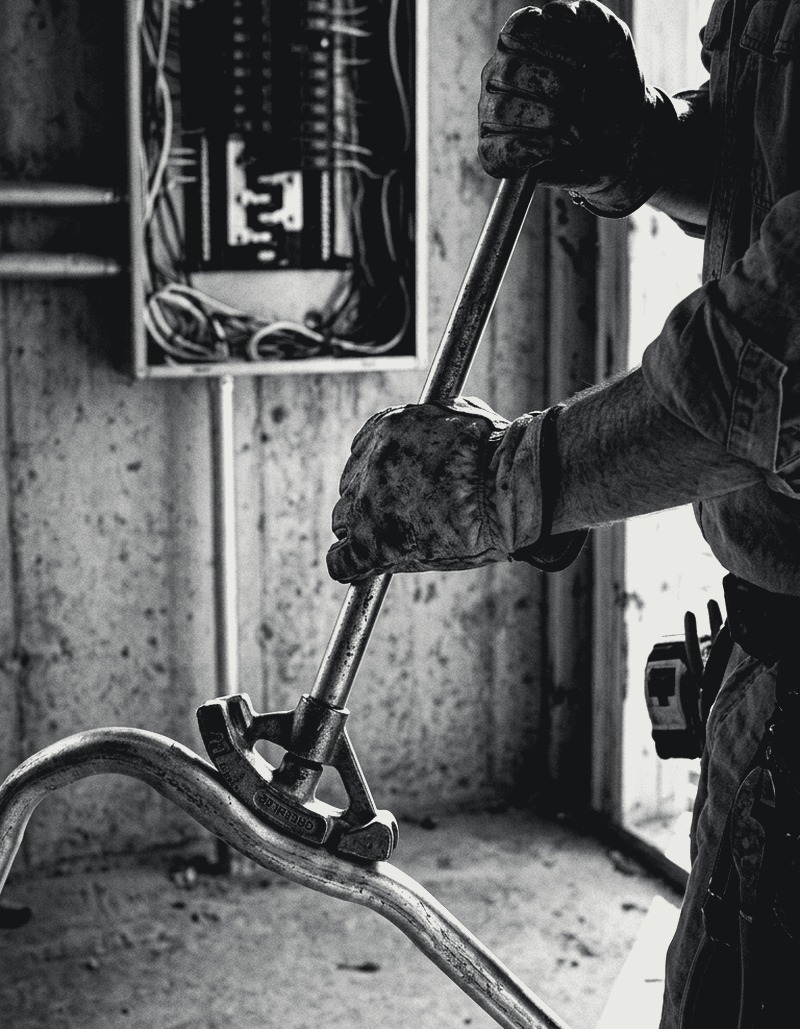 Electrician bending conduit at a panel rough-in