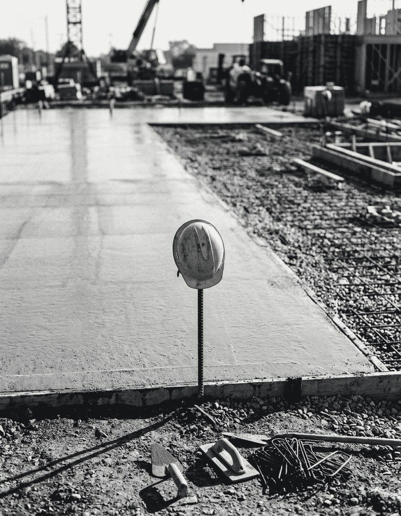 A single hard hat on a rebar stake beside a fresh concrete slab